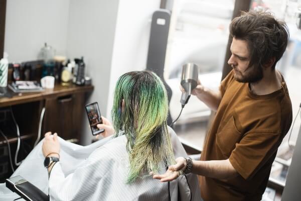 Cosmetologist blow drying client's hair