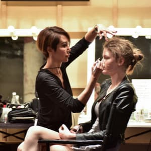 Makeup artist applying eyeshadow to a model backstage