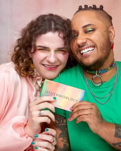 man and woman wearing makeup and holding a promotional card