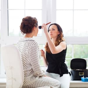 makeup artist applying blush to a woman