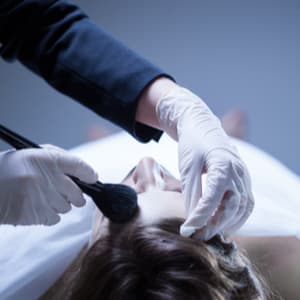 cosmetologist applying makeup to a deceased man