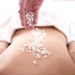 massage therapist sprinkling salt on a woman's back
