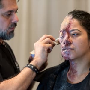 Makeup artist apply zombie Special Effects makeup to a woman's face