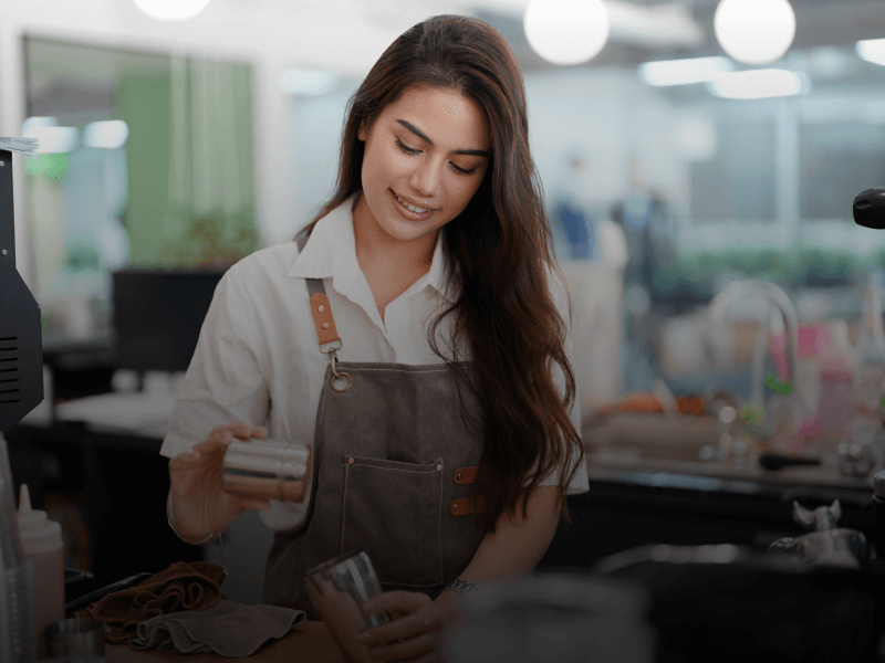 a barista wearing an apron and holding a shaker