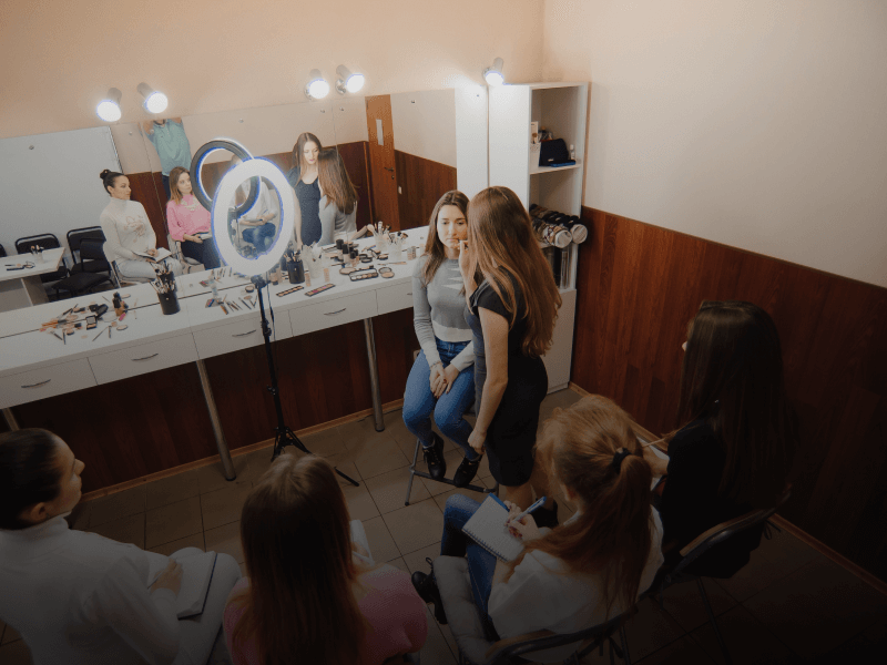 a group of students in a room listening to a cosmetology teacher