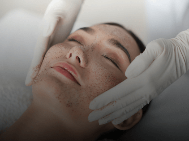 esthetician applying exfoliation facial mask to client
